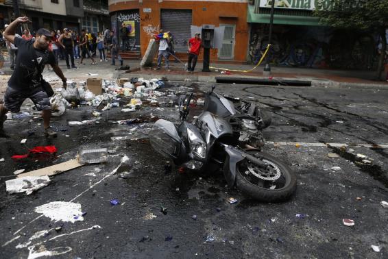 A protester throws stones at a motorcycle after the rider tried to past a barricade in Caracas