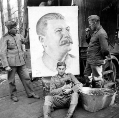 An unusual photograph showing German soldiers in the USSR, before a portrait of Stalin left behind by retreating Soviet troops. The eerie tranquility, accentuated by the puppy, make this a 
