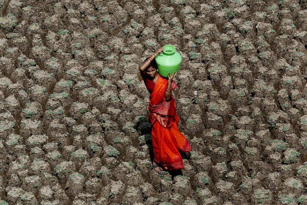 A woman carries home a pot of water, while taking a shortcut across the dry bed of the Usmansagar lake, in Hyderabad, capital of the south Indian Andhra Pradesh state, June 6, 2003. The picture is not about her physical strength in walking long distances to fetch water, but that of her inner strength in ensuring that her family never goes thirsty.  Indians flocked to temples and mosques to pray for rain as the death toll from a heat wave sweeping the country neared surpassed 1200. - SHERWIN CRASTO